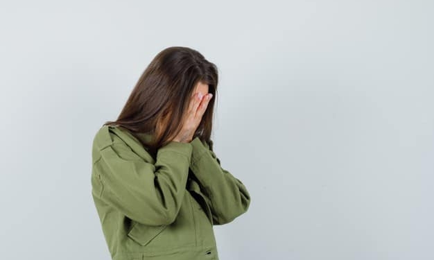 young woman covering hands her face green jacket looking sad front view space text 176474 38056