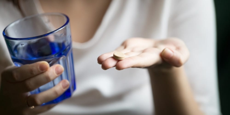 female hands holding pill glass water closeup view