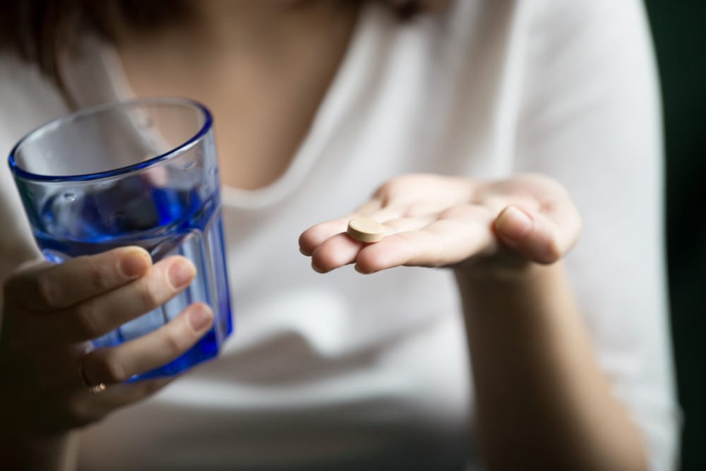 female hands holding pill glass water closeup view