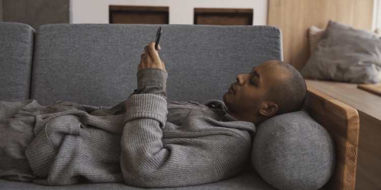 man thuis bank liggen telefoon mobiel