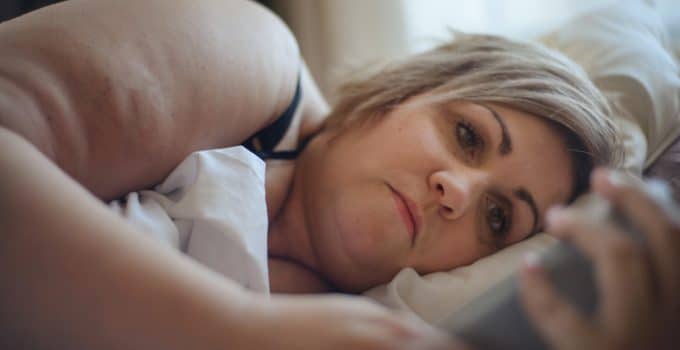 vrouw zwaar dame dik overgewicht slapen liggen bed telefoon corpulent obesitas depressief verdriet