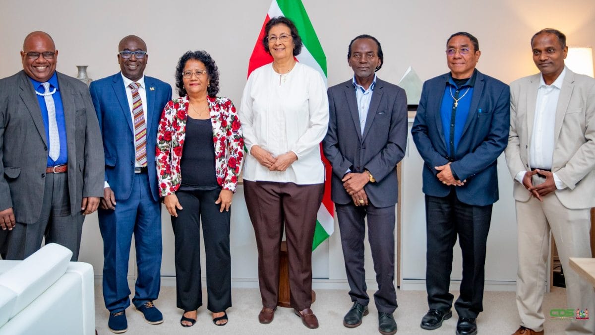 President Jennifer Simons poseert met Edgar Dikan, Armand Jurel, Theresia Cirino, Mike Nerkust, Martin Misiedjan en Sarwan Ramai