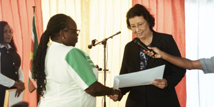 President Jennifer Simons reikt gronddocumenten uit aan verpleegkundigen en leerkrachten bij het ministerie van GBB